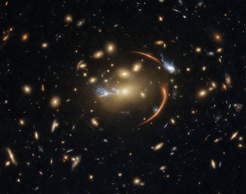 This Hubble image shows the galaxy cluster MACS J0138.0-2155, which is so massive that its gravity bent and magnified light streaming not only from an extremely distant background galaxy but also from a supernova event in this galaxy. The color image was made using observations from eight different filters spread across Hubble’s Advanced Camera for Surveys (ACS) and Wide Field Camera 3 (WFC3). The color results from assigning different hues to each monochromatic image associated with an individual filter. I