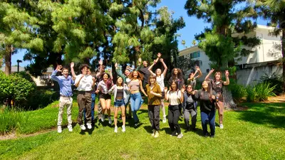 CASSI 2023 interns jump on the grass at the Observatories campus. 